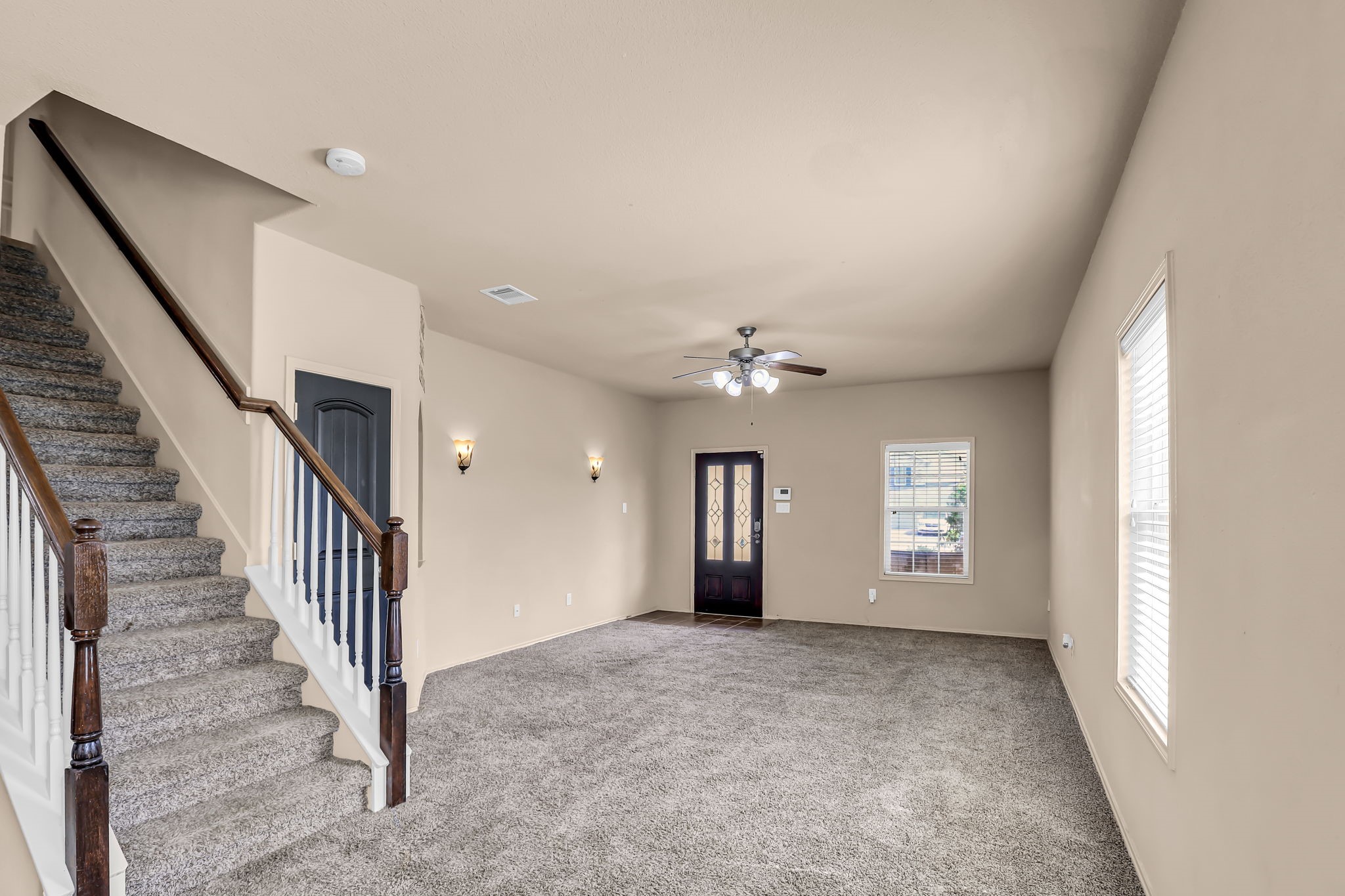 21307 Carleen Creek Trail Spring, TX 77379 - Photo 4 of 25 Bright and spacious living area with neutral walls and carpet, featuring a ceiling fan and natural light from multiple windows.