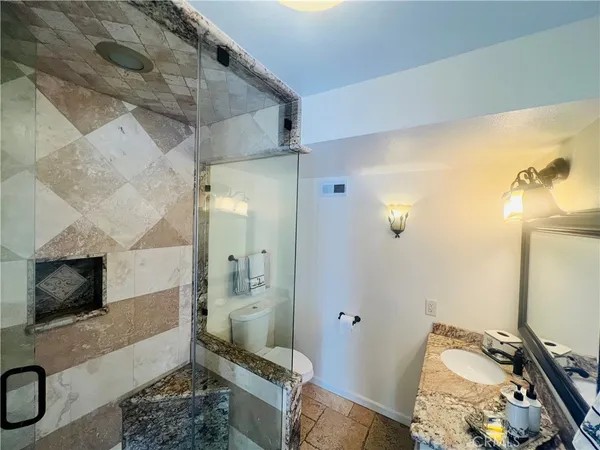 a spacious bathroom with a granite countertop sink a mirror and shower