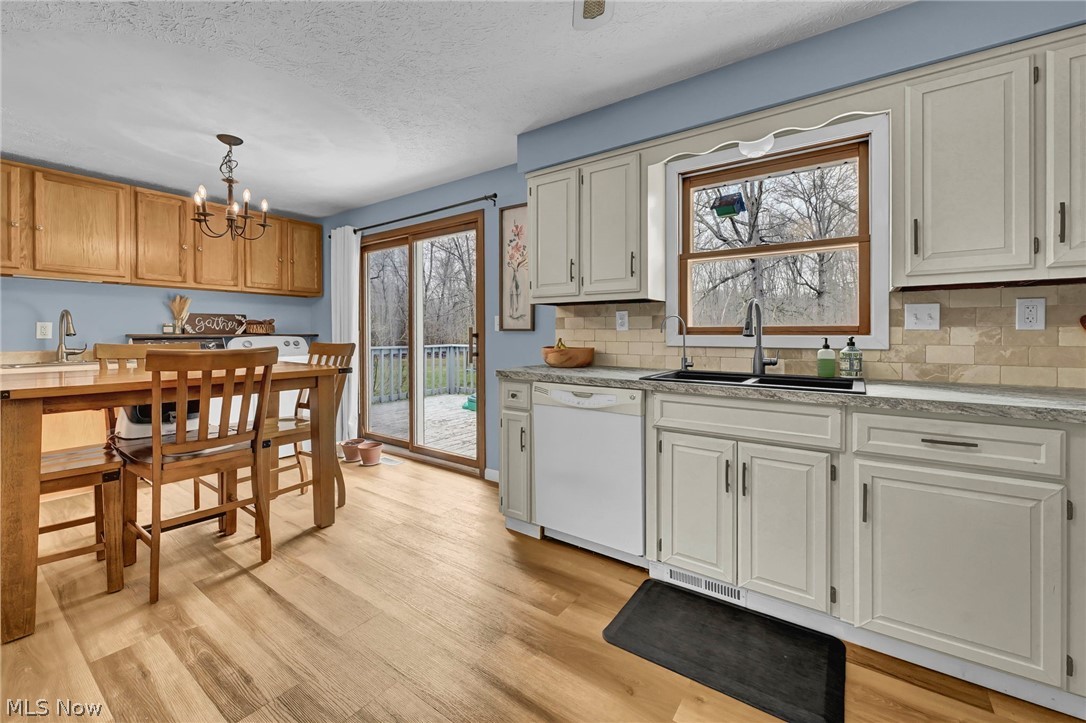 259 East Ohio Avenue Rittman, OH 44270 - Photo 11 of 41 Kitchen featuring a chandelier, dishwasher, light wood-style floors, a textured ceiling, and decorative backsplash