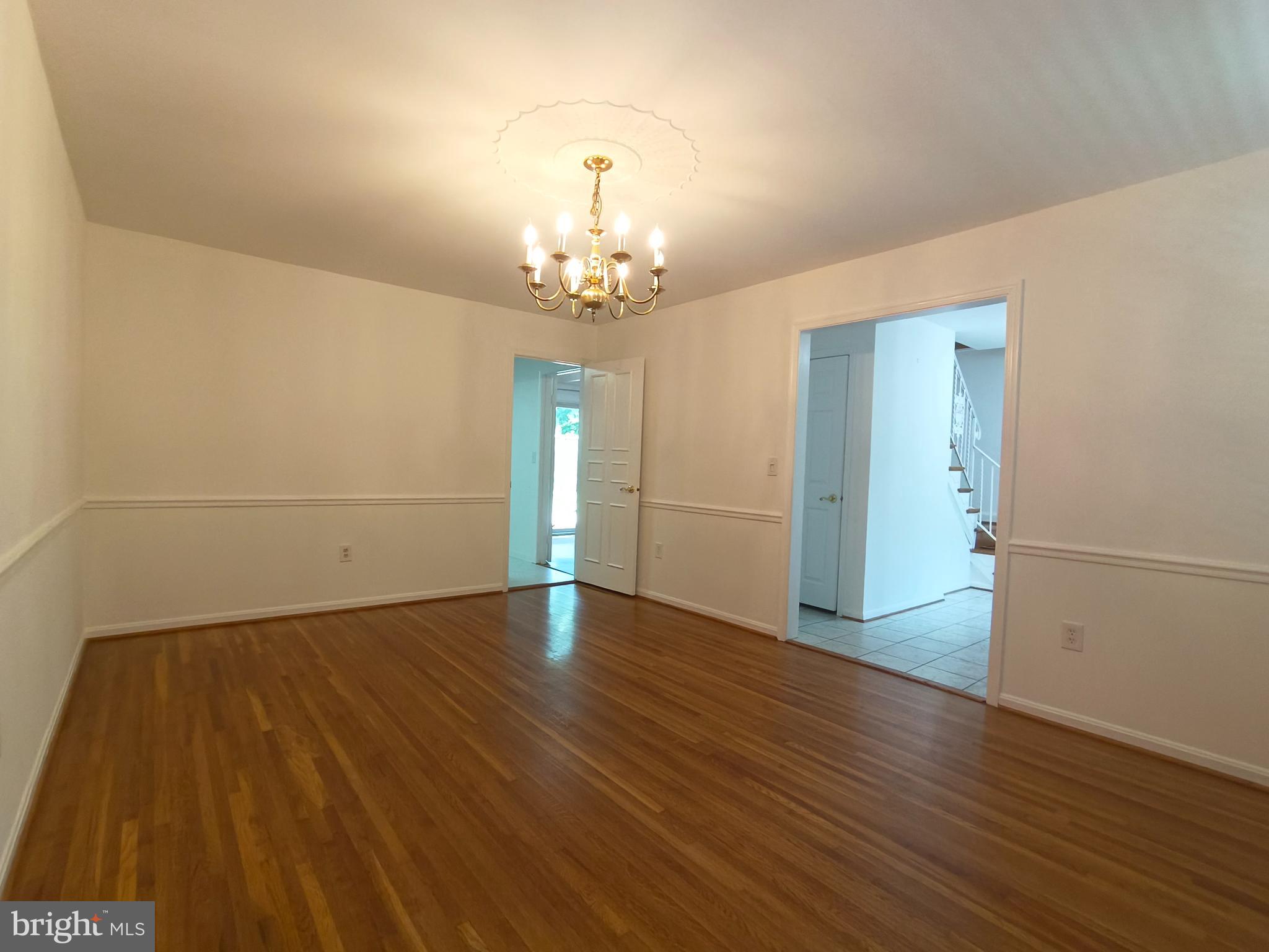 8835 Tuckerman Lane Potomac, MD 20854 - Photo 14 of 46 an empty room with wooden floor and chandelier