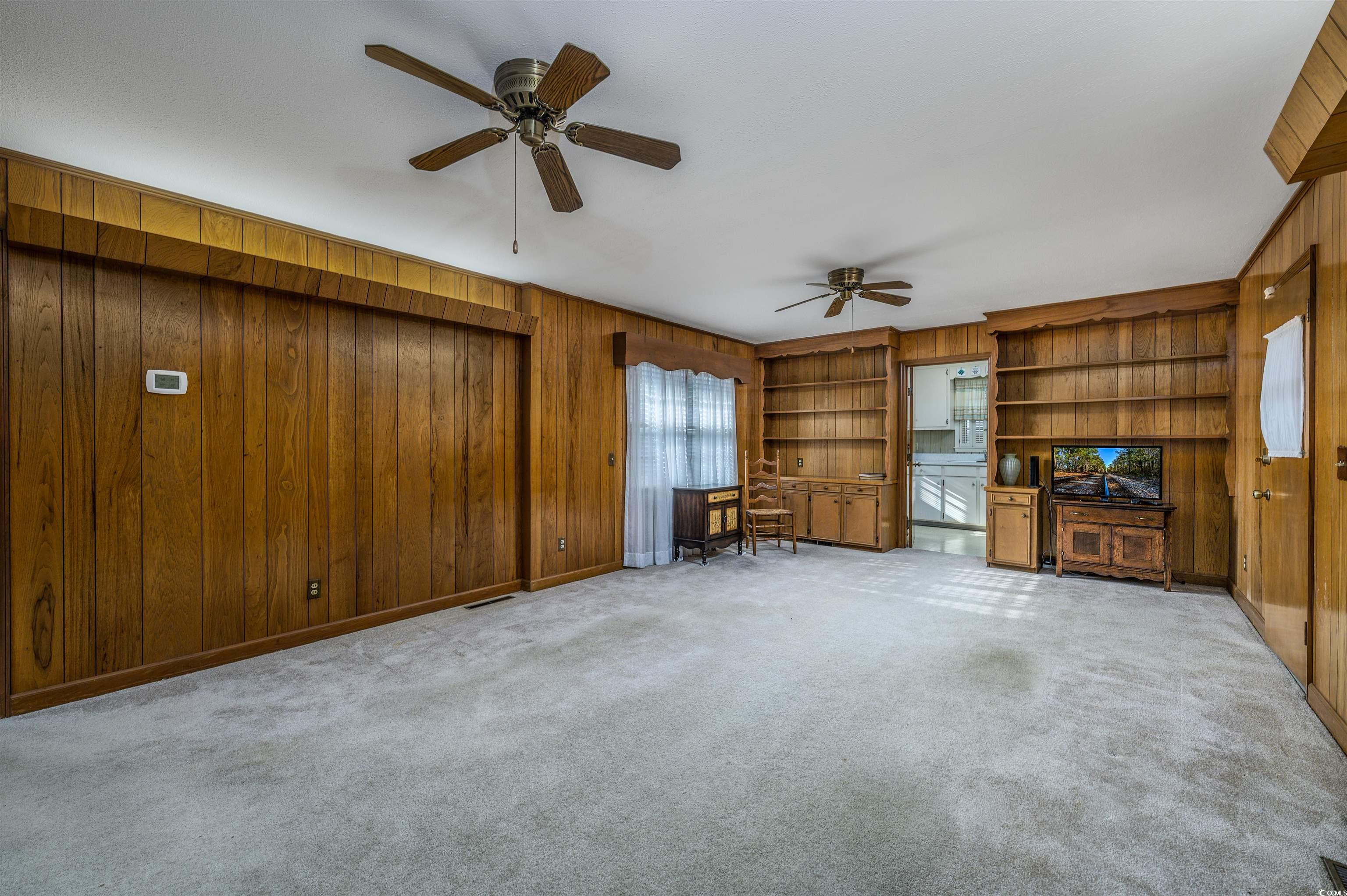 1870 Highway 348 Loris, SC 29569 - Photo 11 of 34 Unfurnished family room with wood walls, built in features, light colored carpet, and ceiling fan