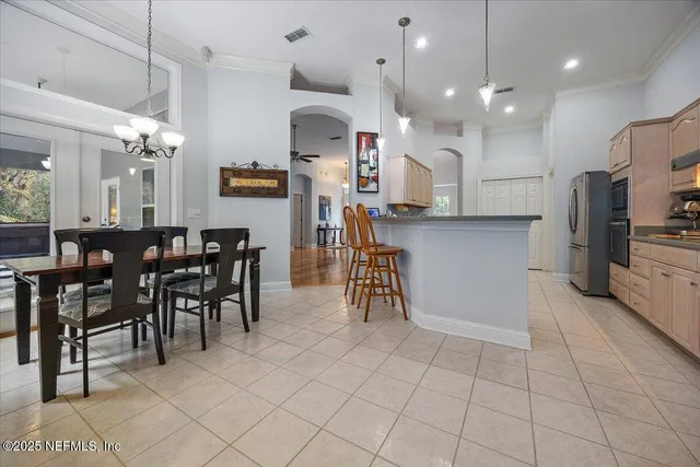a kitchen with stainless steel appliances kitchen island granite countertop a table chairs and a refrigerator