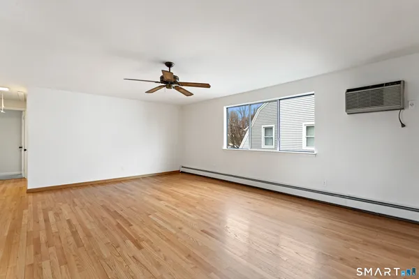 a view of an empty room with window and wooden floor