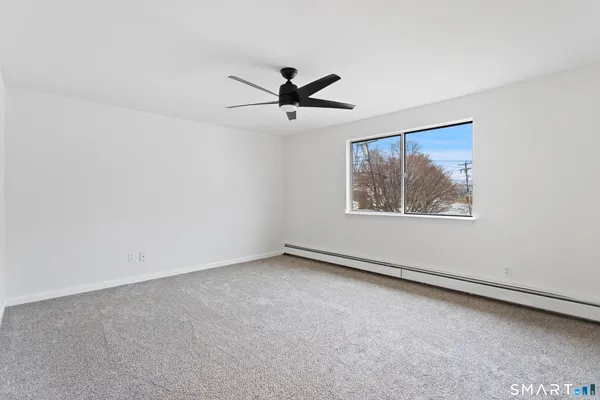 an empty room with windows and fan