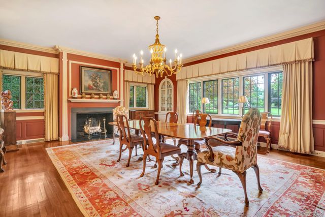 a dining room with wooden floor a chandelier a wooden table and chairs