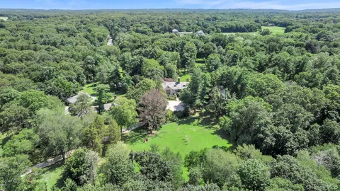 an aerial view of residential house with outdoor space and trees all around