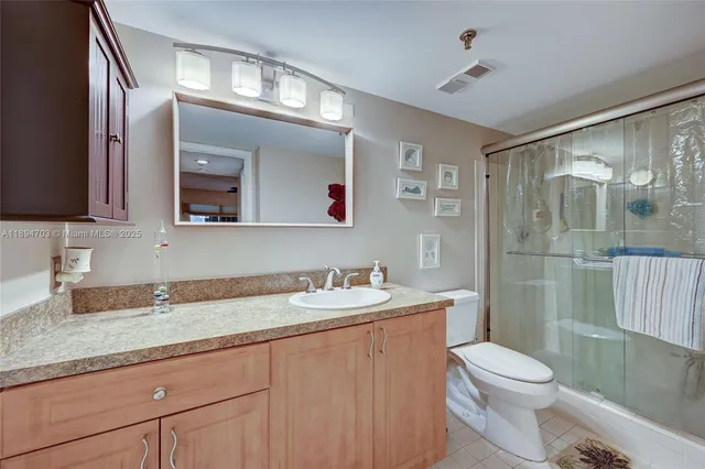 a bathroom with a granite countertop sink mirror vanity and toilet