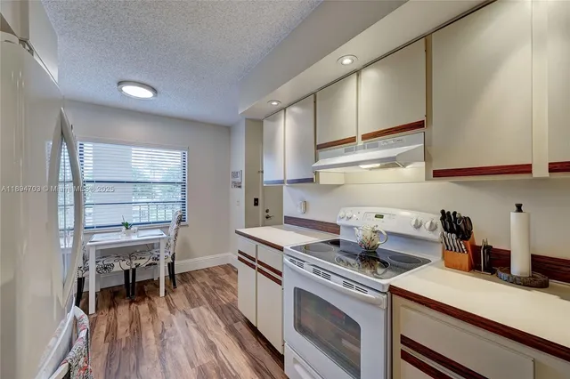a kitchen with cabinets wooden floor and stainless steel appliances