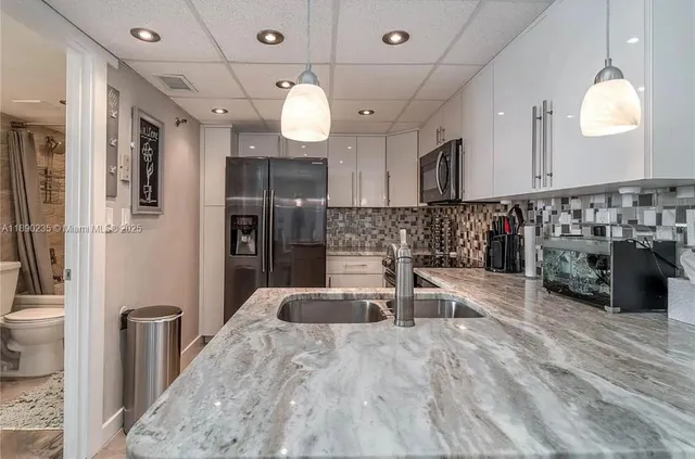 a large kitchen with stainless steel appliances kitchen island granite countertop a sink and a refrigerator