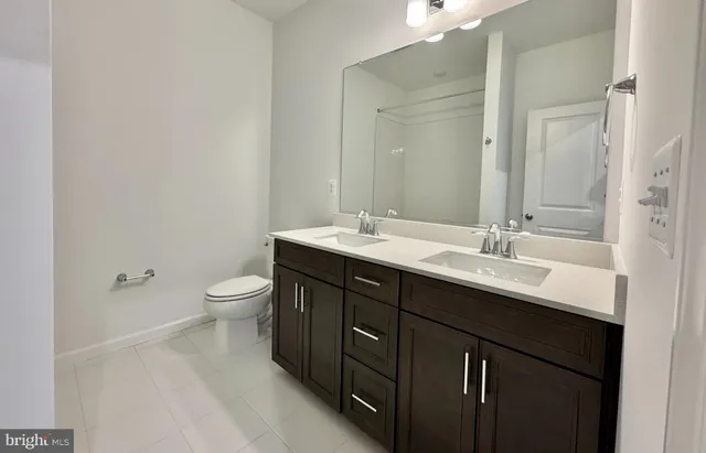 a bathroom with a double vanity sink toilet and a mirror