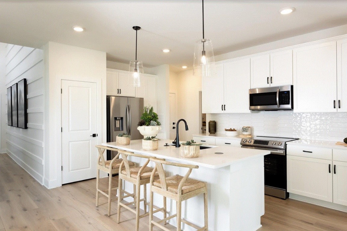 a kitchen with stainless steel appliances kitchen island granite countertop a sink a refrigerator a stove a dining table and chairs with wooden floor