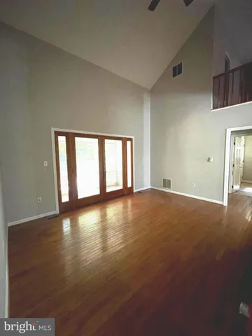 a view of empty room with wooden floor and fan