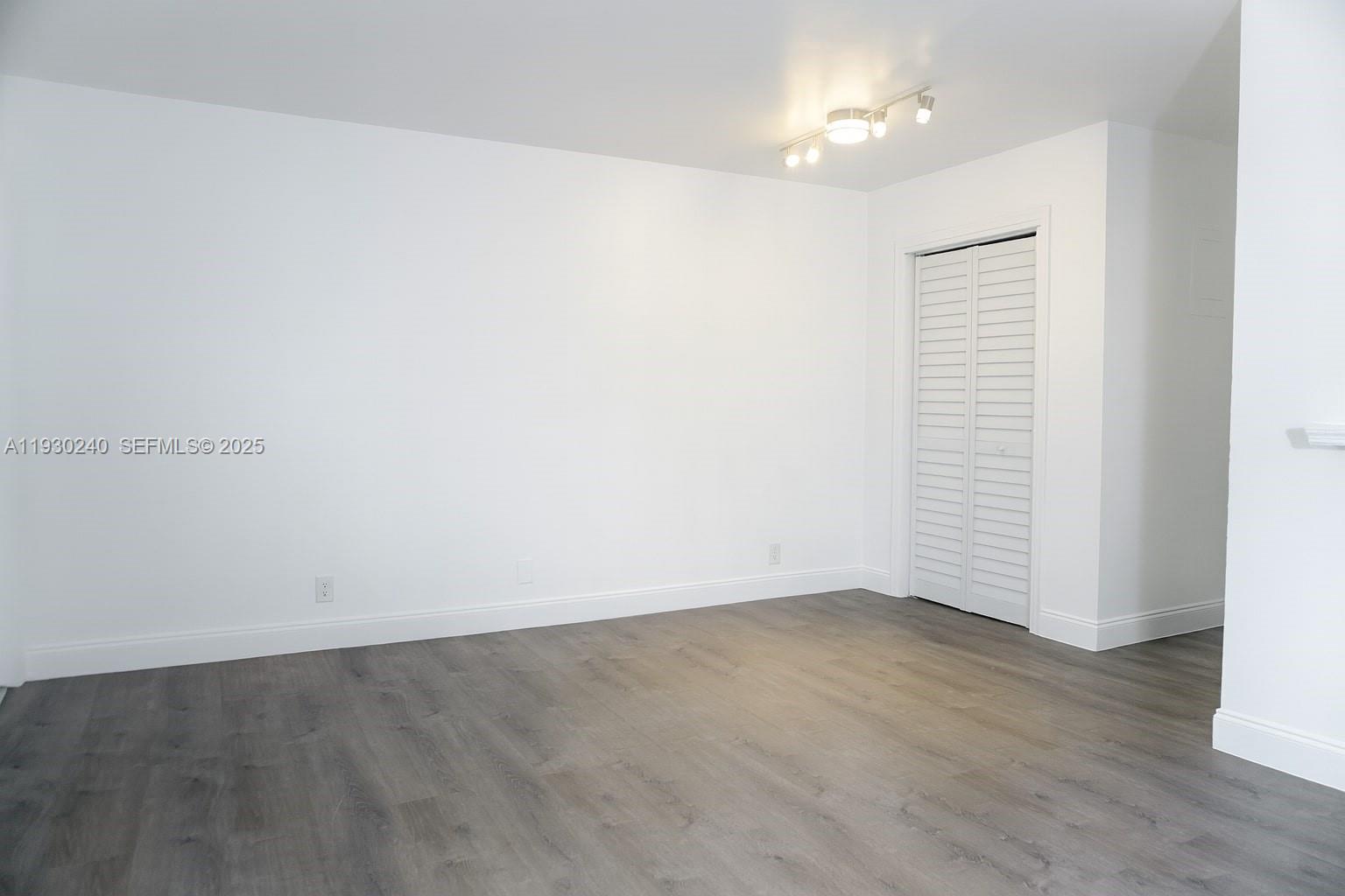 749 Southeast 15th Street, Unit 8 Fort Lauderdale, FL 33316 - Photo 5 of 15 an empty room with wooden floor chandelier fan and windows