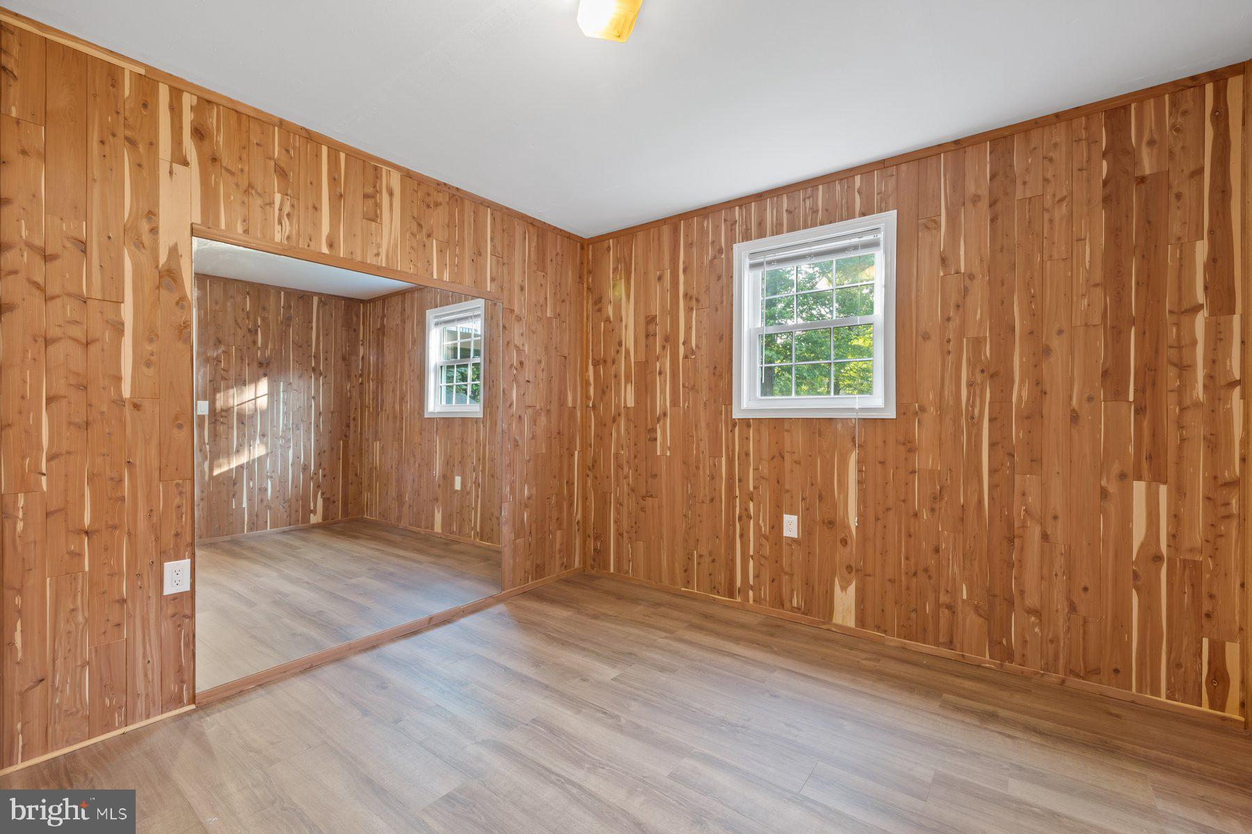8304 Grainfield Road Severn, MD 21144 - Photo 25 of 49 an empty room with wooden floor and windows with curtains view