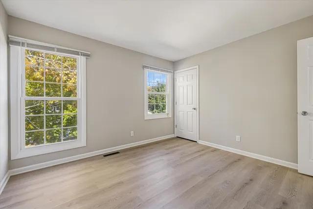 an empty room with wooden floor and windows