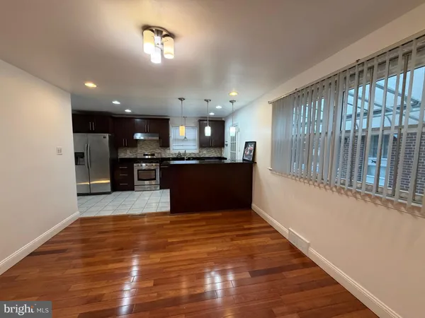 a large kitchen with kitchen island a island wooden floor and stainless steel appliances