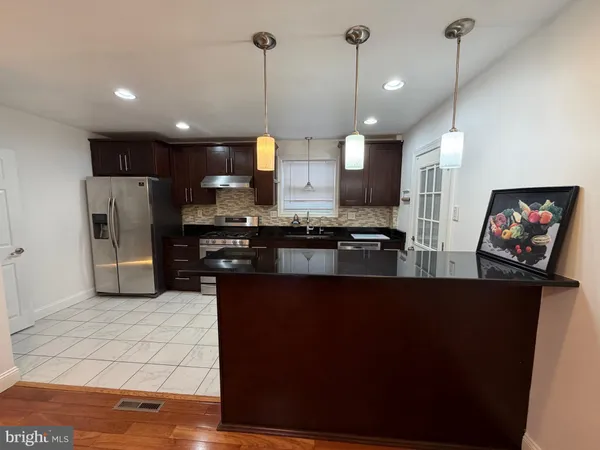 a kitchen with stainless steel appliances granite countertop a refrigerator a stove a sink and a microwave