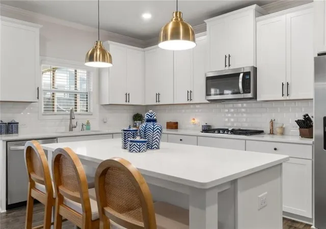 a kitchen with stainless steel appliances granite countertop a stove a sink a microwave a refrigerator a center island and cabinets