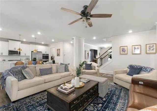 a living room with furniture kitchen view and a wooden floor