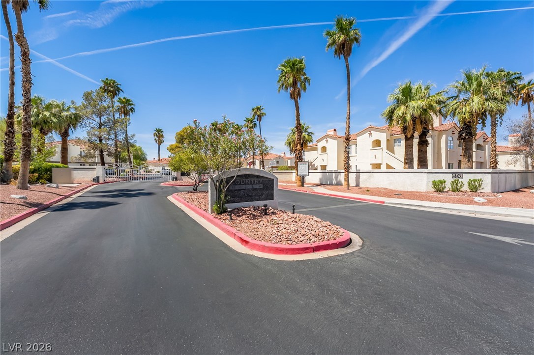 698 South Racetrack Road, Unit 1512 Henderson, NV 89015 - Photo 29 of 30 Gated neighborhood entrance lined with mature palm trees under clear blue skies.