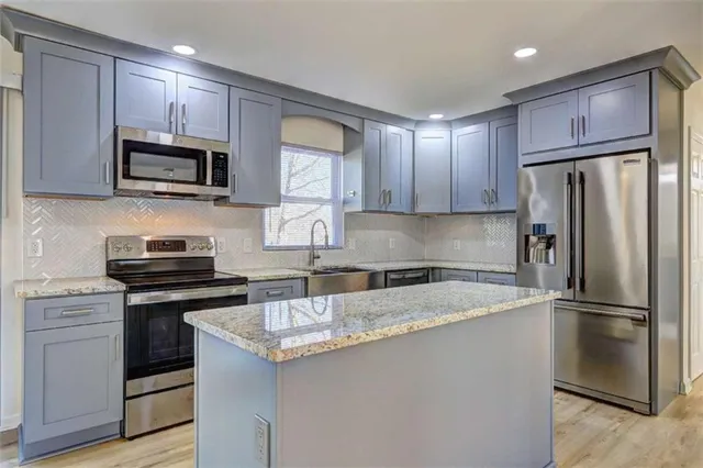 a kitchen with stainless steel appliances granite countertop a stove a refrigerator and a sink