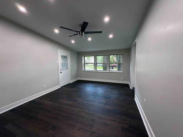 an empty room with wooden floor and windows