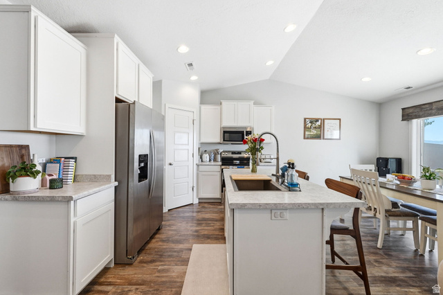1175 Silver Hollow Road Syracuse, UT 84075 - Photo 10 of 34 Modern kitchen featuring a central island with an undermount sink, light-toned countertops, and wood-finish flooring