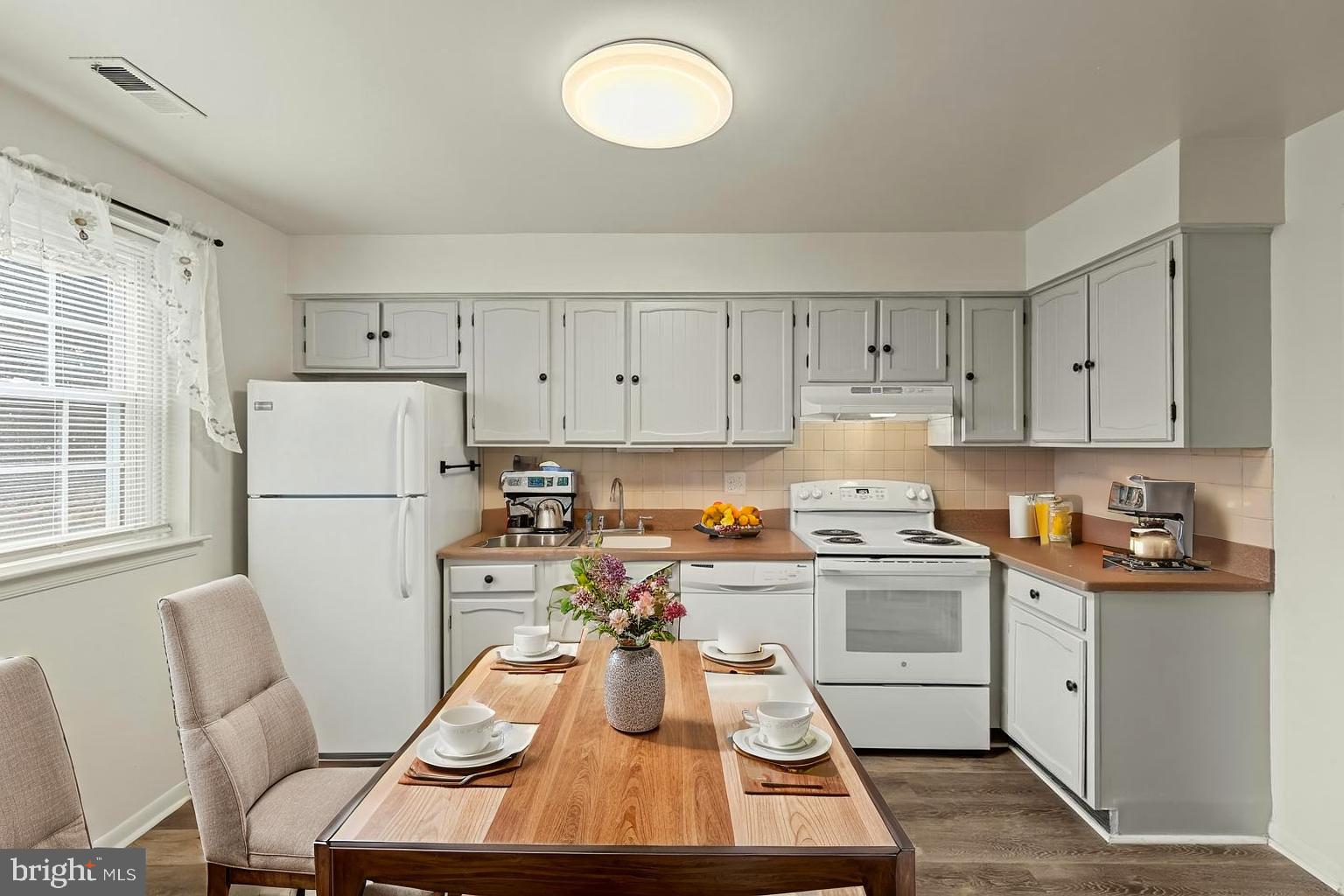 10 Kettle Court, Unit 76F Windsor Mill, MD 21244 - Photo 6 of 29 a kitchen with a refrigerator a stove a sink dishwasher and white cabinets with wooden floor