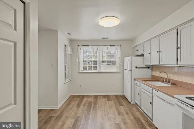 a view of a kitchen with white cabinets and wooden floor