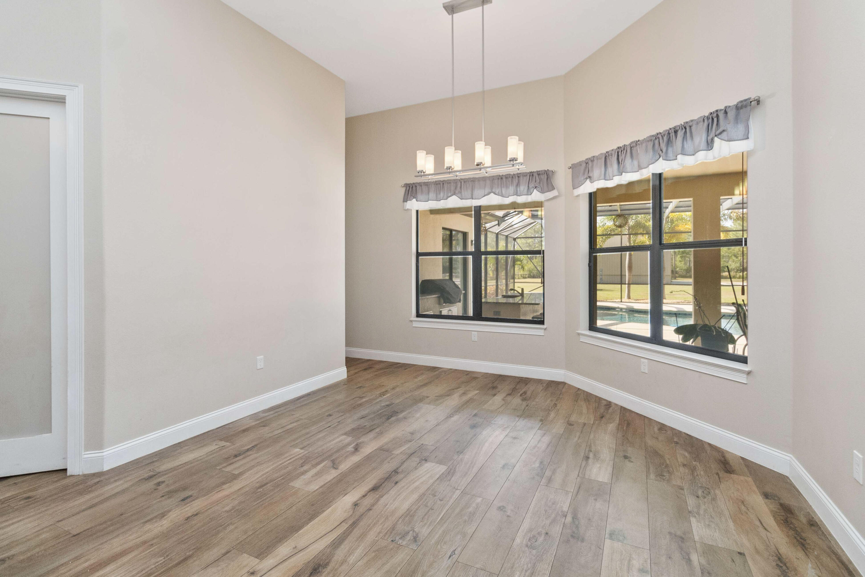 3640 Corey Road Grant Valkaria, FL 32950 - Photo 23 of 77 an empty room with wooden floor chandelier and windows
