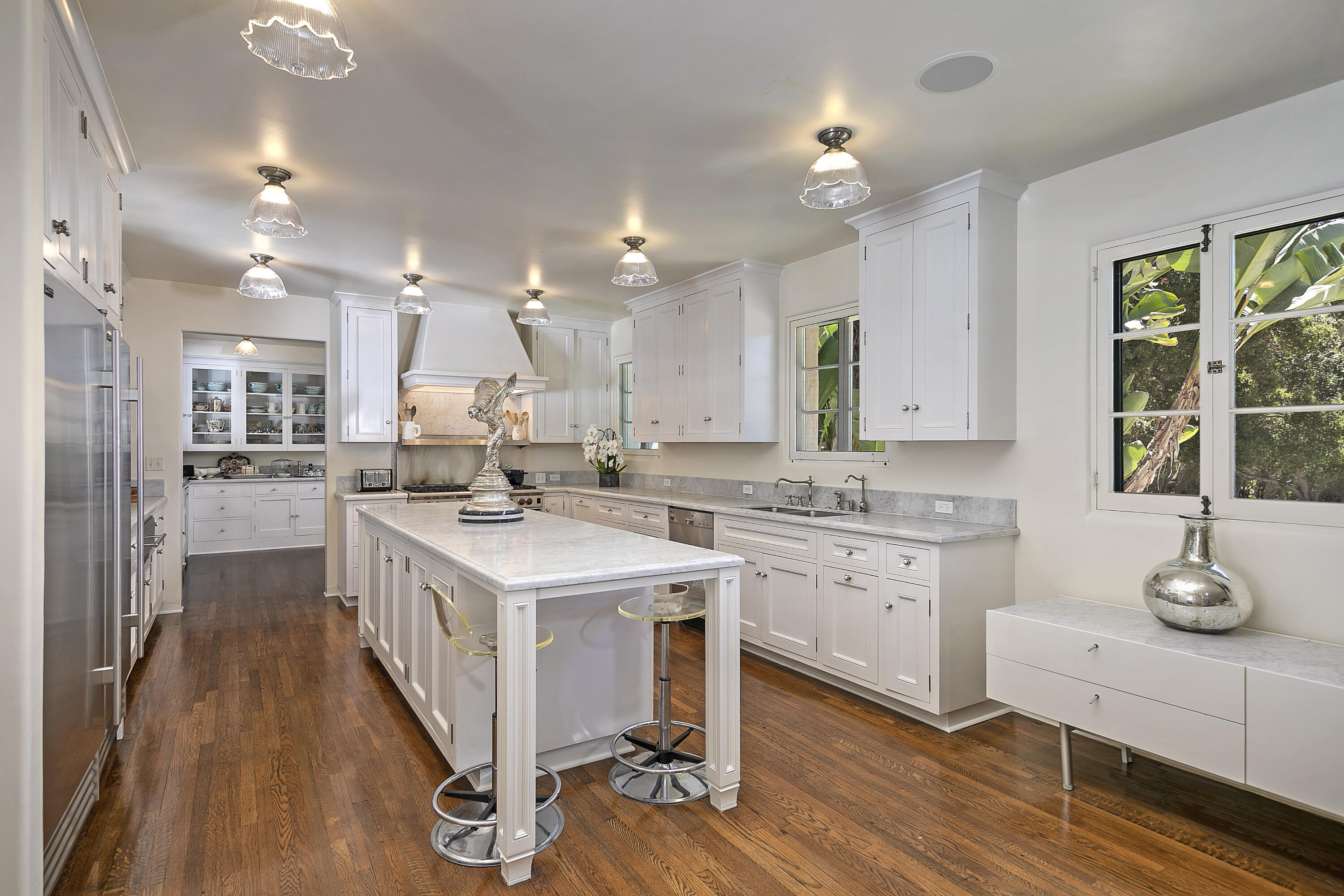 2925 Sycamore Canyon Road Montecito, CA 93108 - Photo 7 of 19 a kitchen with a sink stove a refrigerator and white cabinets with wooden floor