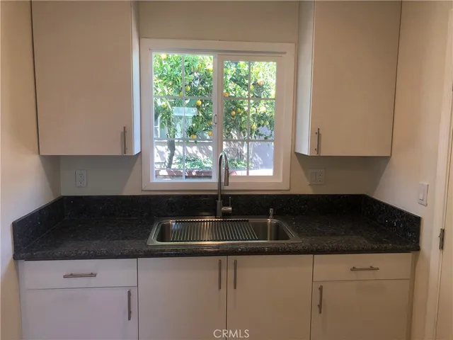 a kitchen with granite countertop white cabinets and a sink