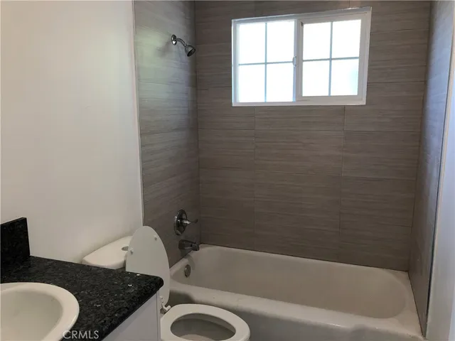 a bathroom with a granite countertop sink toilet and bathtub