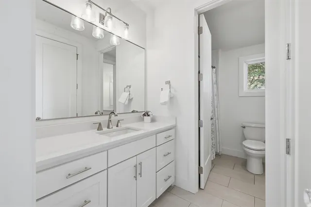 a spacious bathroom with a double vanity sink a toilet and a mirror