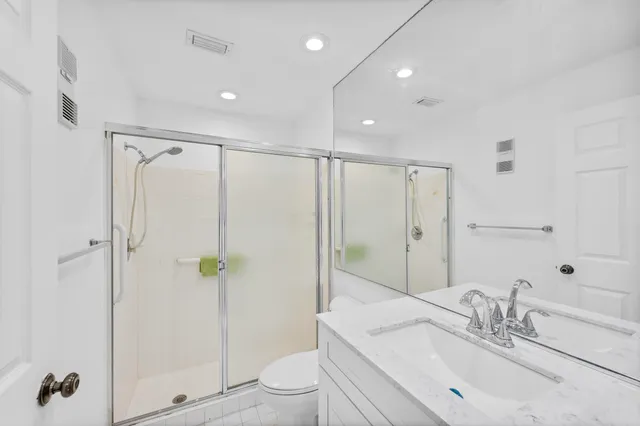 a bathroom with a shower sink vanity mirror and toilet