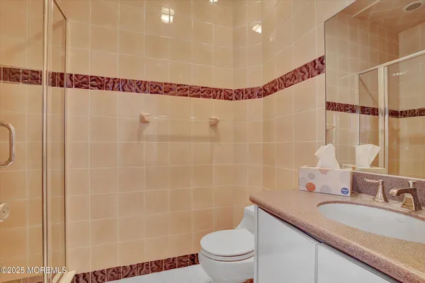 a bathroom with a sink a toilet a mirror and shower