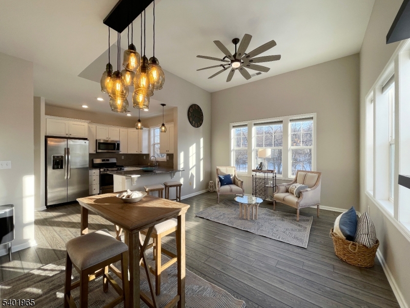 a living room with couches a fireplace and kitchen view with wooden floor