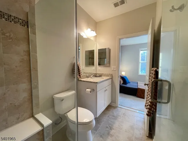 a bathroom with a granite countertop sink mirror vanity and toilet
