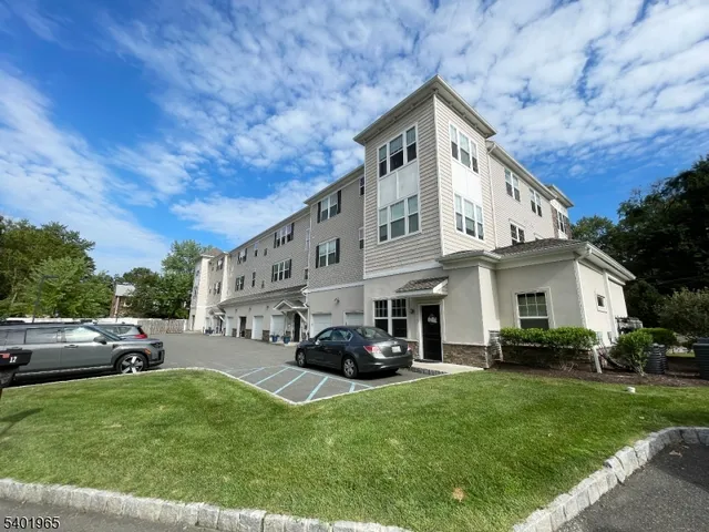 a view of a white house with a big yard plants and large trees