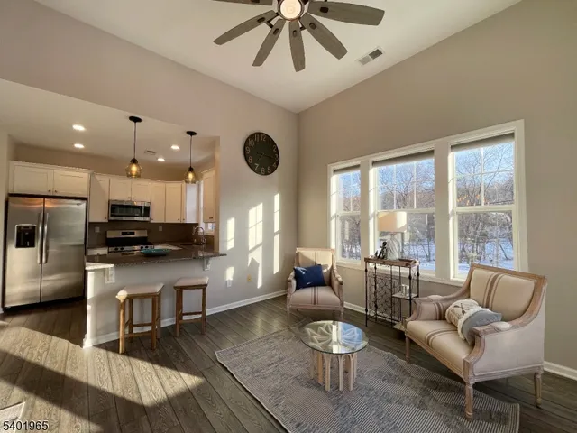 a living room kitchen with a dining table wooden floor and a large window