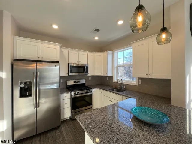 a kitchen with stainless steel appliances granite countertop a refrigerator a sink a stove a dining table and chairs