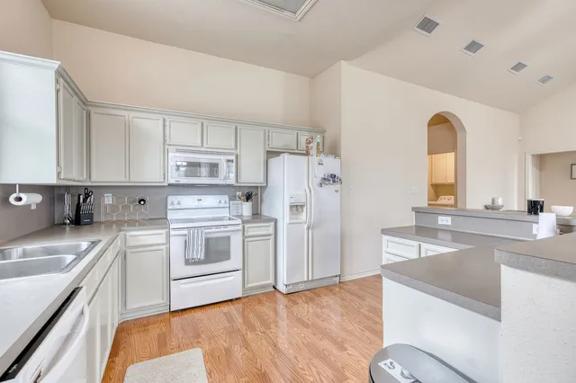 a kitchen with stainless steel appliances granite countertop a refrigerator a stove and white cabinets with wooden floor