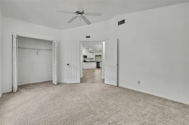 an empty room with windows and fan