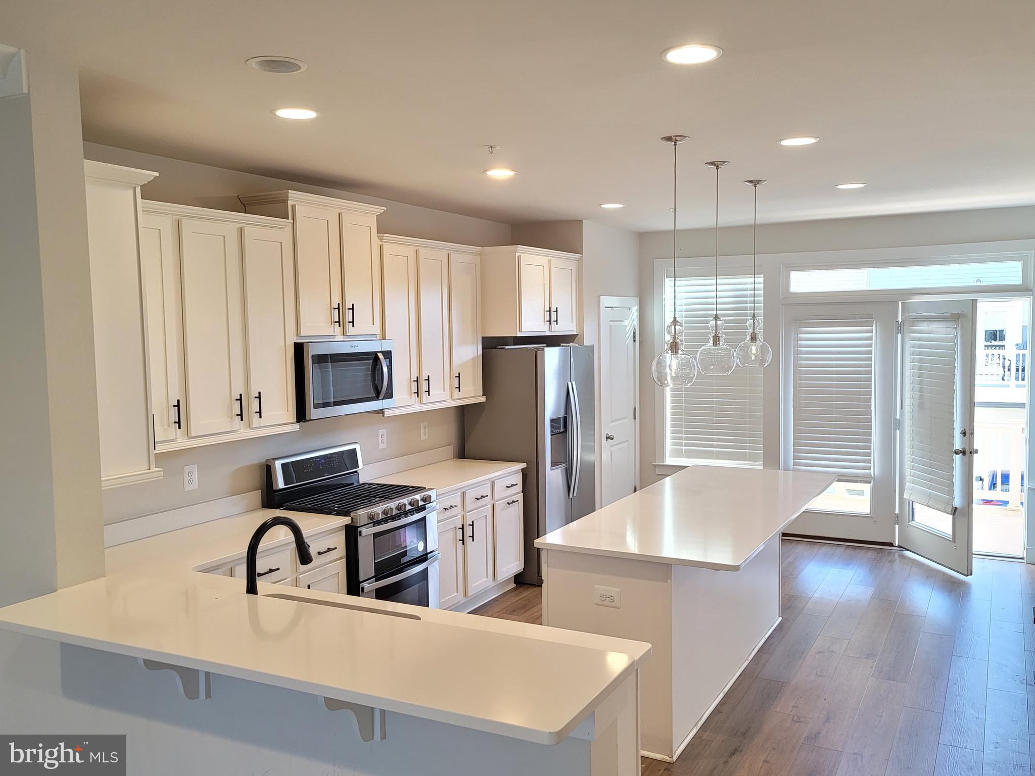 8571 Red Sage Way South Frederick, MD 21704 - Photo 14 of 17 a very nice looking kitchen with stainless steel appliances granite countertop a refrigerator a sink a stove and white cabinets with wooden floor