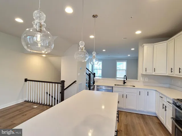 a large kitchen with stainless steel appliances granite countertop a stove a sink a refrigerator and white cabinets granite countertops with wooden floor