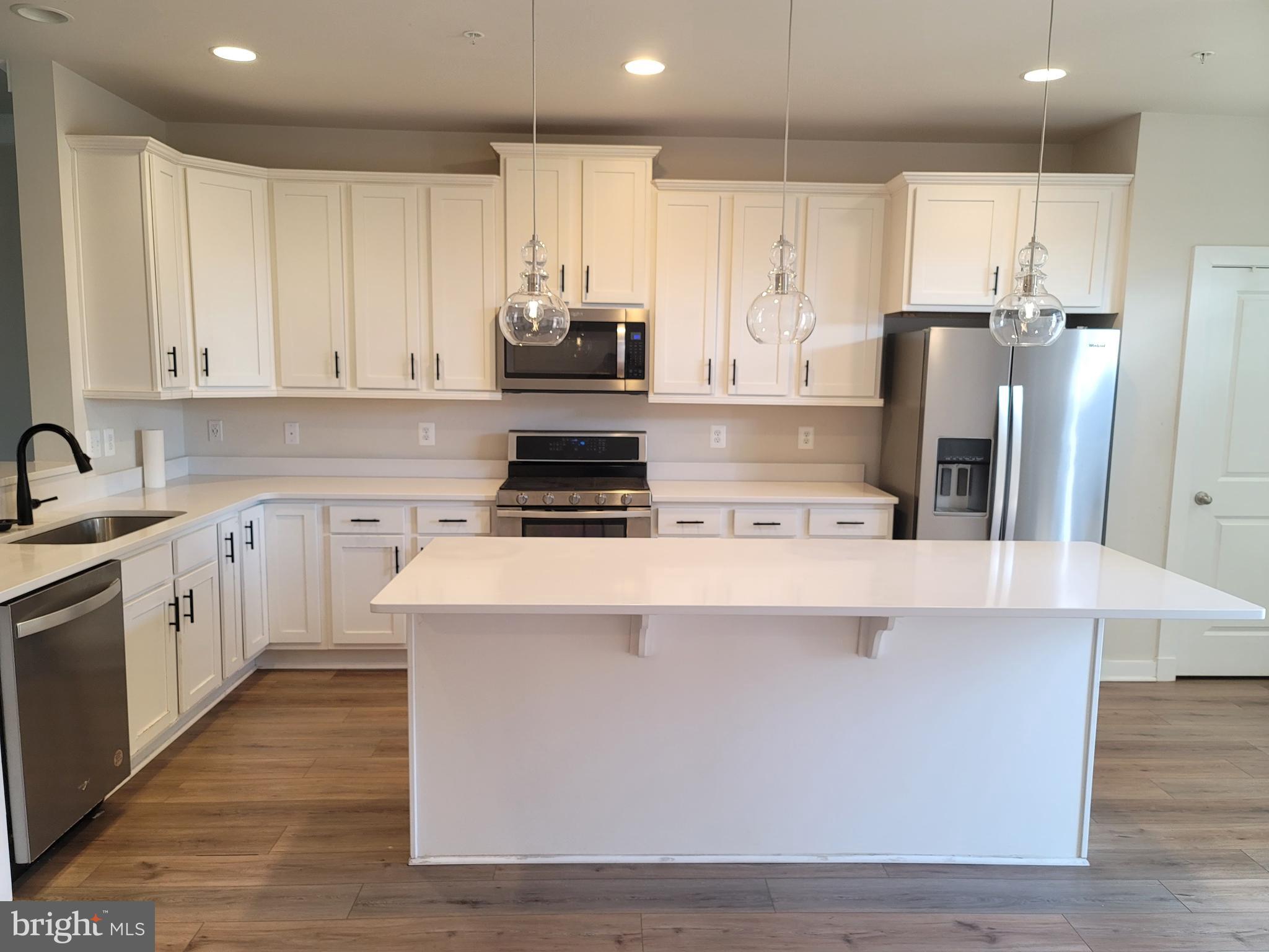 8571 Red Sage Way South Frederick, MD 21704 - Photo 6 of 17 a kitchen with kitchen island white cabinets and stainless steel appliances