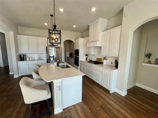 a kitchen with stainless steel appliances kitchen island wooden floors and white cabinets
