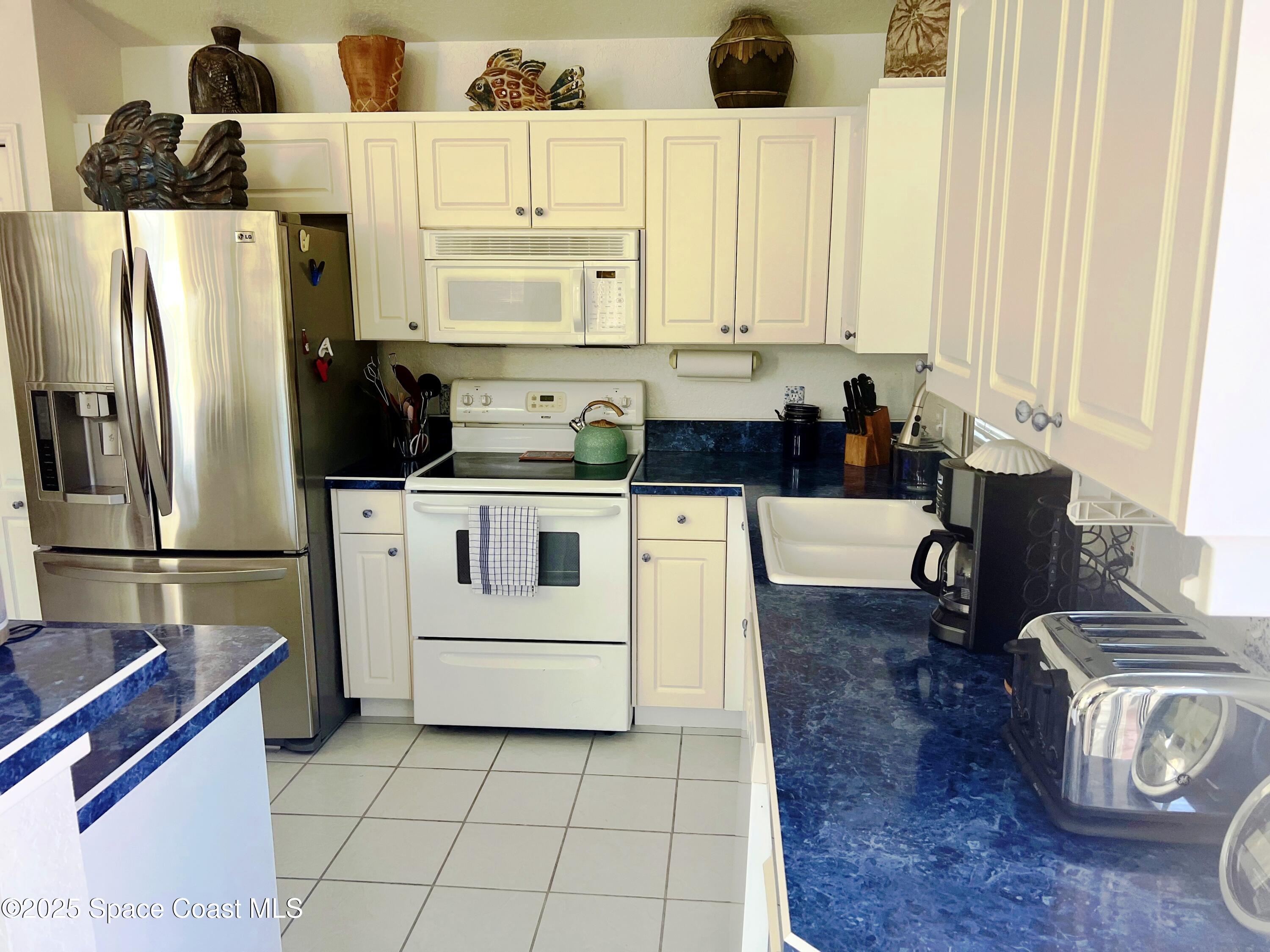 150 Sandy Shoes Drive Melbourne Beach, FL 32951 - Photo 16 of 31 a kitchen with a sink a stove and refrigerator