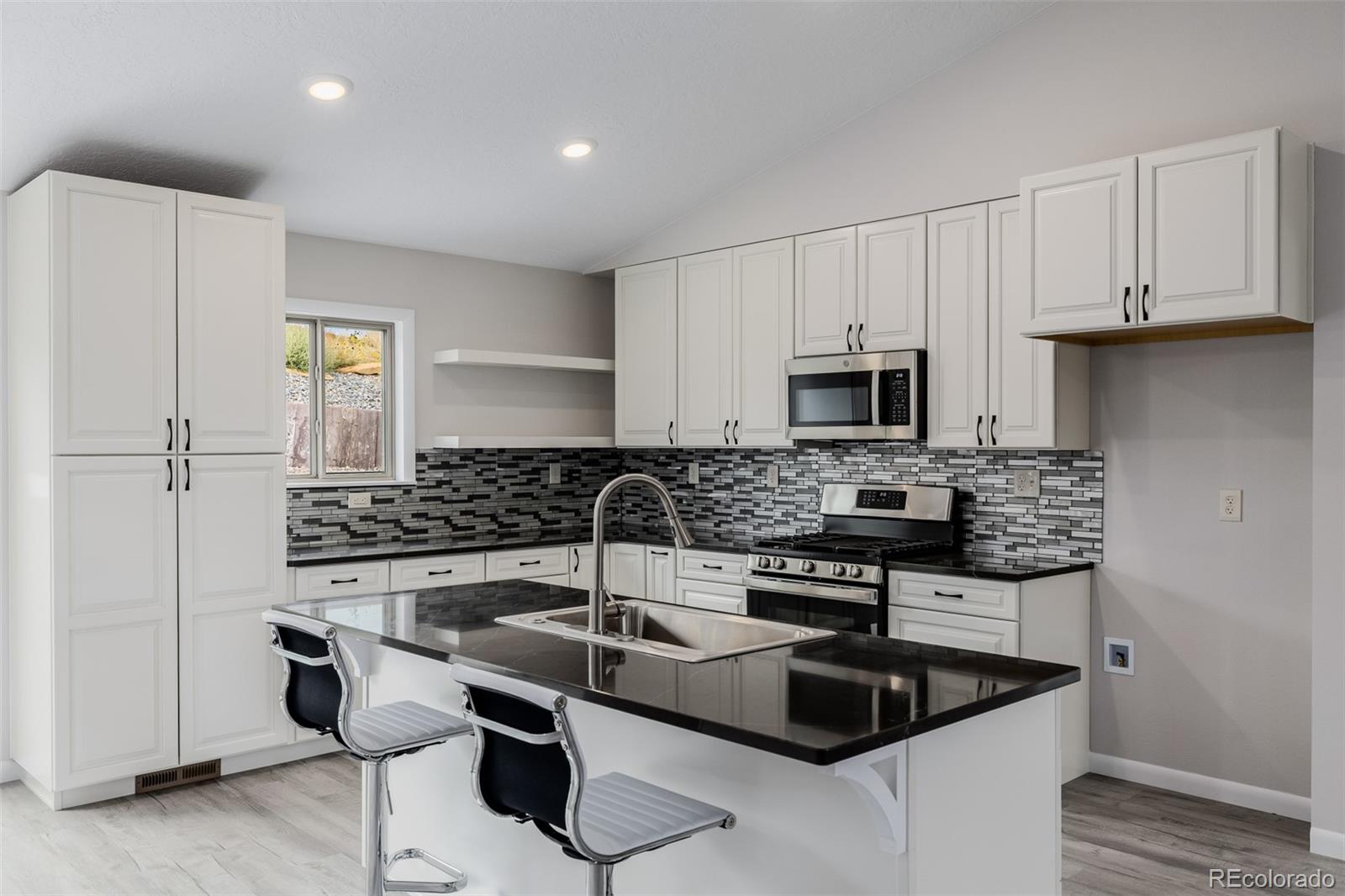 407 Double Tree Drive Greeley, CO 80634 - Photo 12 of 50 a kitchen with granite countertop a sink stove and cabinets