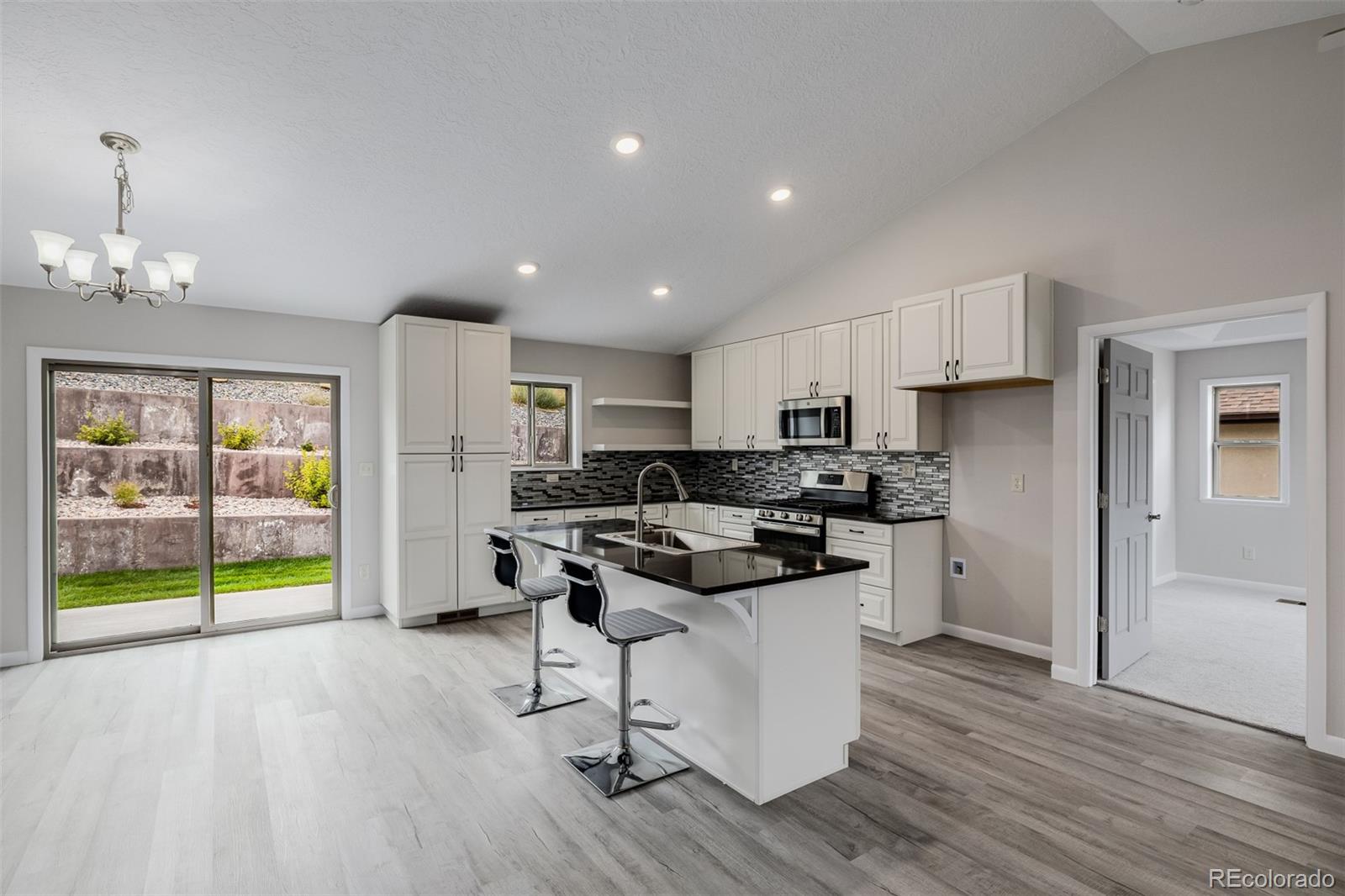 407 Double Tree Drive Greeley, CO 80634 - Photo 14 of 50 a kitchen with a sink a stove a refrigerator and white cabinets with wooden floor